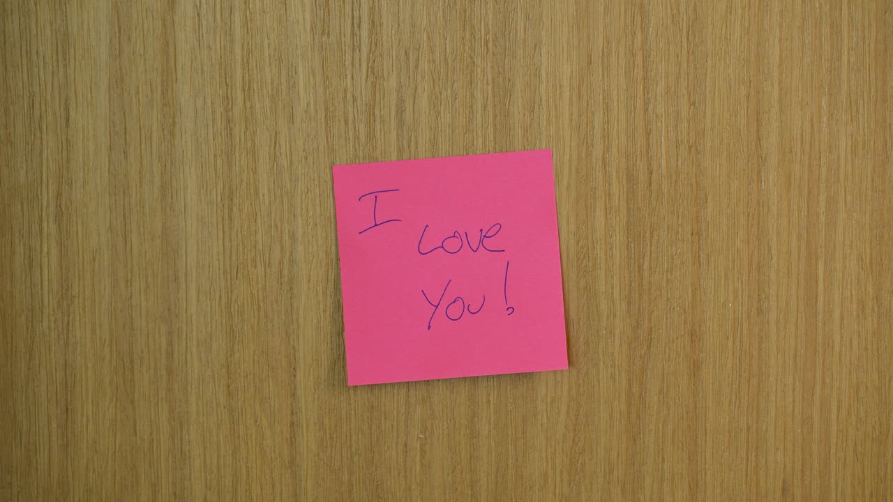 Intimate close-up of a hand gently peeling an 'I Love You' sticky note from a wooden door, highlighting the tender gesture in warm lighting, emphasizing love and connection