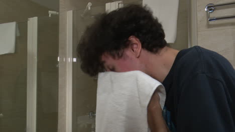 young man washing face in hotel bathroom