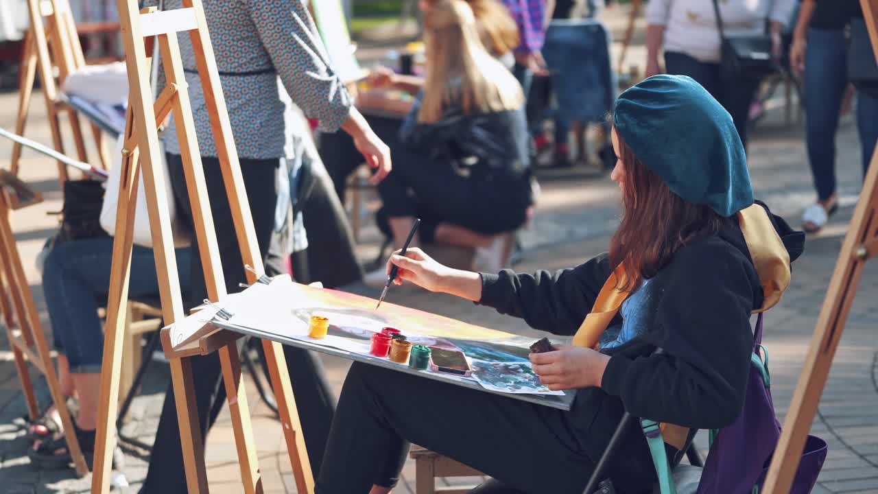 Young woman painting picture. Street artist painting picture in the city