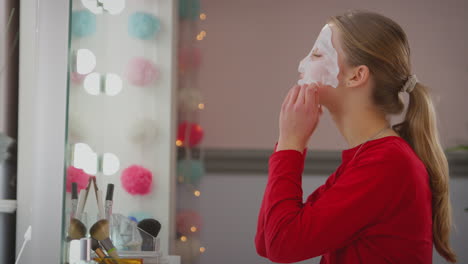 Adolescente-Vistiendo-Pijamas-Poniéndose-Mascarilla-En-El-Espejo-Del-Dormitorio-En-Casa---Filmada-En-Cámara-Lenta