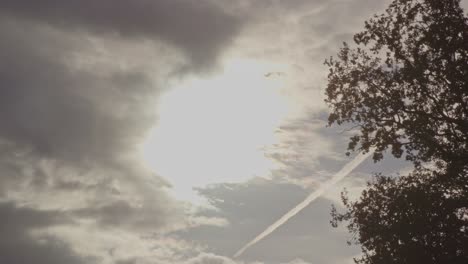 Eine-Hell-Leuchtende-Sonne,-Die-Durch-Dunkle-Wolken-Bricht,-Vor-Der-Ein-Vogel-Fliegt