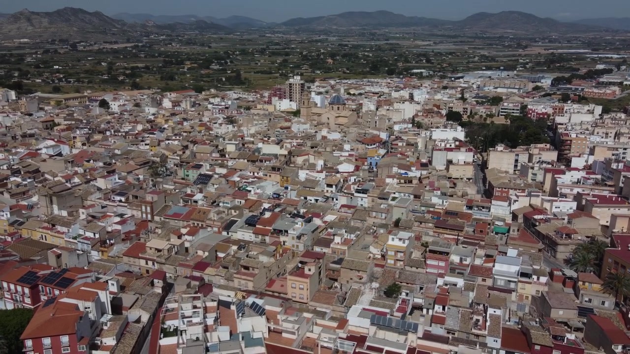 Vídeo aéreo orbitando a tradicional cidade antiga de Aspe, Espanha. Tomada cinematográfica de drone exibindo arquitetura histórica, telhados de telha e ruas europeias estreitas em um dia ensolarado