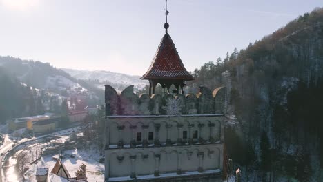 Aerial-orbit-around-the-main-tower-of-Bran's-Casle-in-Brasov,-Romania-during-a-sunny-winter-afternoon