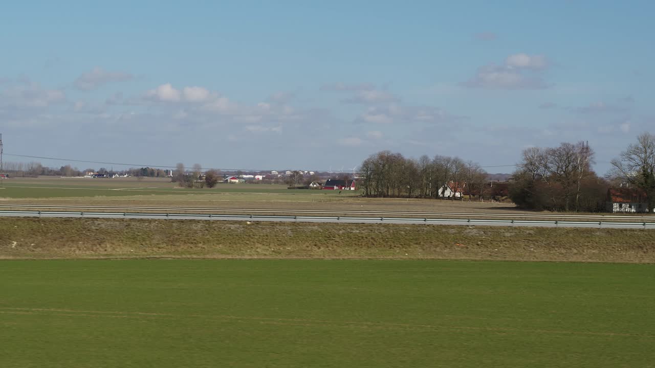 el dron lateral vuela cerca de un campo al lado de una autopista con tráfico - los coches pasan