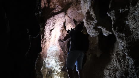 archaeologist man shining a flashlight in a cave archaeologist man shining a flashlight in a cave speleology dungeons dark tunnel underground excavations