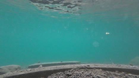 la cámara submarina se eleva desde el lago con agua turquesa cristalina que revela el paisaje de invierno con nieve cayendo en el lago