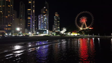 approaching drone movement to the coastal balneário camboriú city in nighttime with lit ferris wheel, santa catarina, brazil