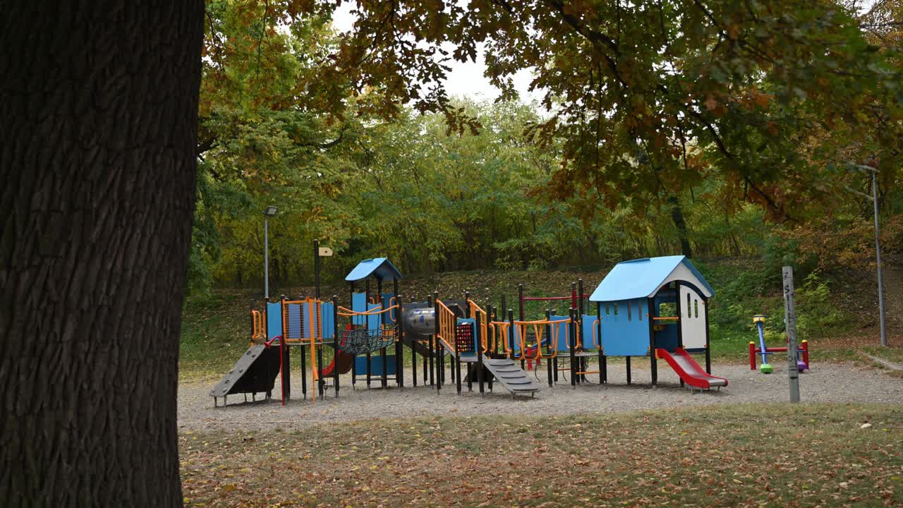 Deserted playground surrounded by trees in fall season, peaceful early morning atmosphere. 4K with selective focus