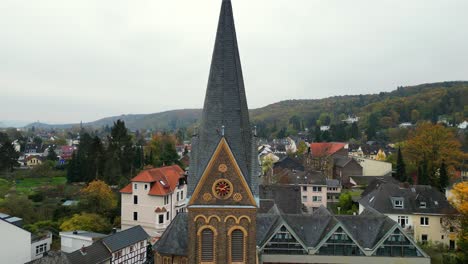 zurückziehende drohnenaufnahme der kirche in dottendorf, deutschland, mit einer goldenen uhr und der nachbarschaft im hintergrund