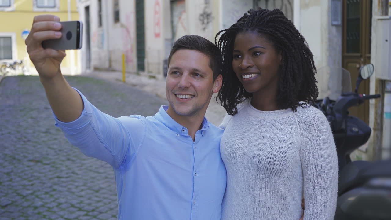 Smiling young couple taking selfie with smartphone.