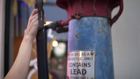 Close-up-Of-Female-Hand-Lifting-An-Old-Vintage-Gas-Nozzle-From-An-Antique-Flea-Market-In-Bangkok-Thailand