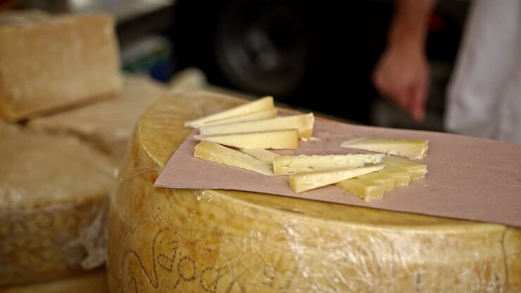 Elder person hand taking cheese sample at local market, close up shot