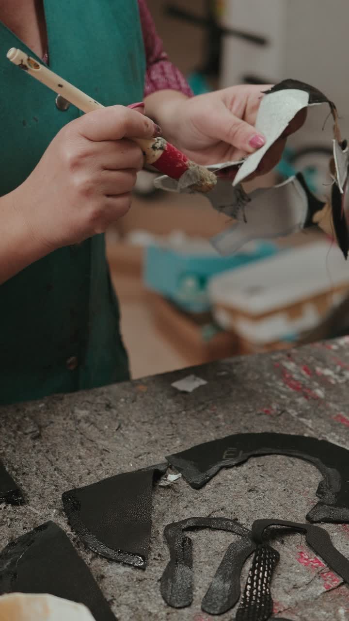 Vertical closeup of artisan gluing leather parts during handmade footwear production