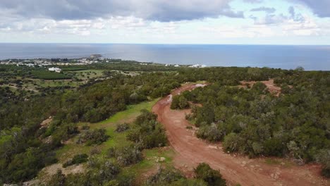 aerial drone shot of the akamas peninsula of cyprus in paphos following a dirt path high in the hills with the sea and cloudy sky in the distance