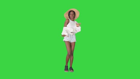 cheerful african american girl in a straw hat dancing on a green screen, chroma key