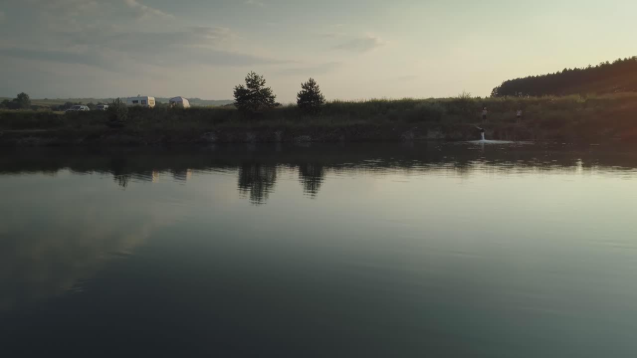 Smooth surface of lake reflecting sky with clouds, sunshine from right corner