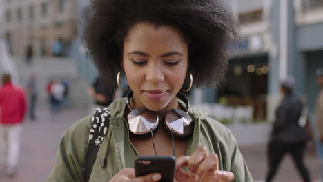 retrato en cámara lenta de una joven afroamericana de moda que usa una aplicación de teléfono inteligente, envía mensajes de texto, navega por las redes sociales y disfruta del estilo de vida urbano