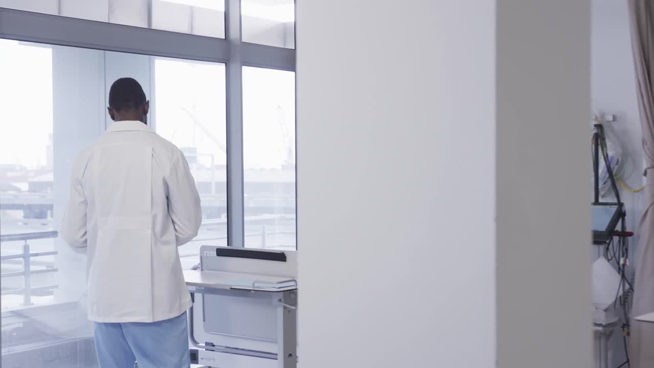Médico afro-americano usando um tablet no quarto do hospital, em câmara lenta.