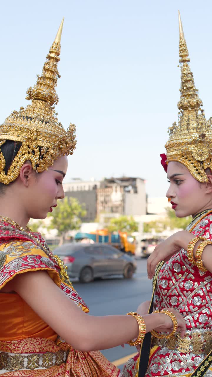 Bailarines de Khon tailandeses con tocados dorados ajustan elaborados trajes al aire libre bajo una luz natural brillante.