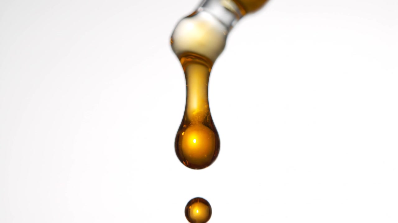 Amber Liquid Dropping from a Glass Pipette Close Up