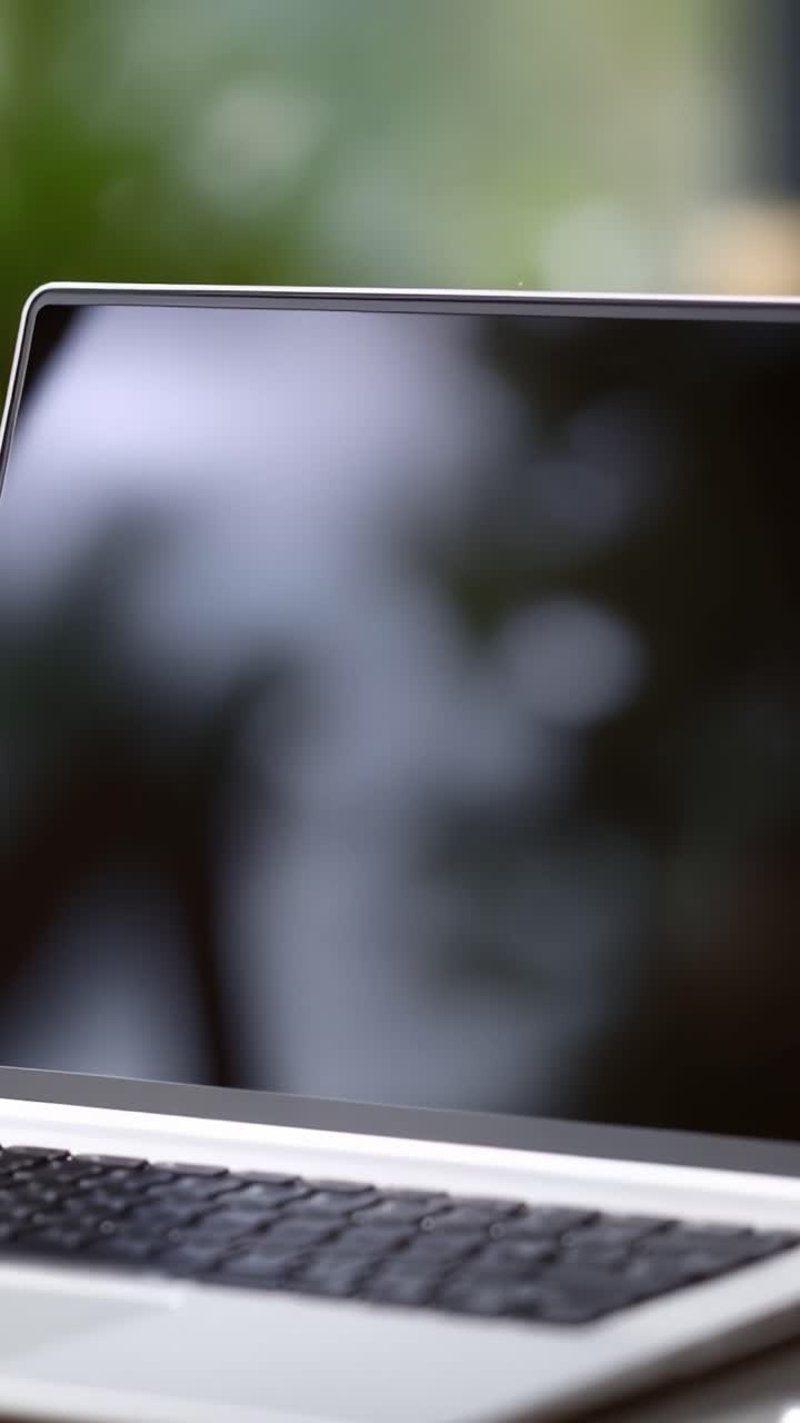 Et hyggeligt arbejdsområde med en bog, briller og en bærbar computer omgivet af grønne planter: Perfekte rammer for inspiration og fokuseret produktivitet.
