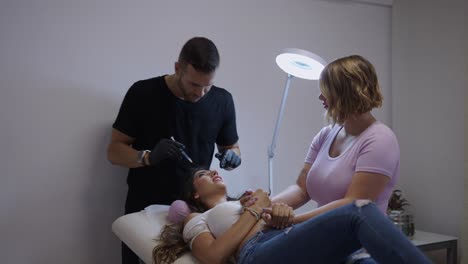 a beauty professional performs a treatment on a client in a salon with assistance