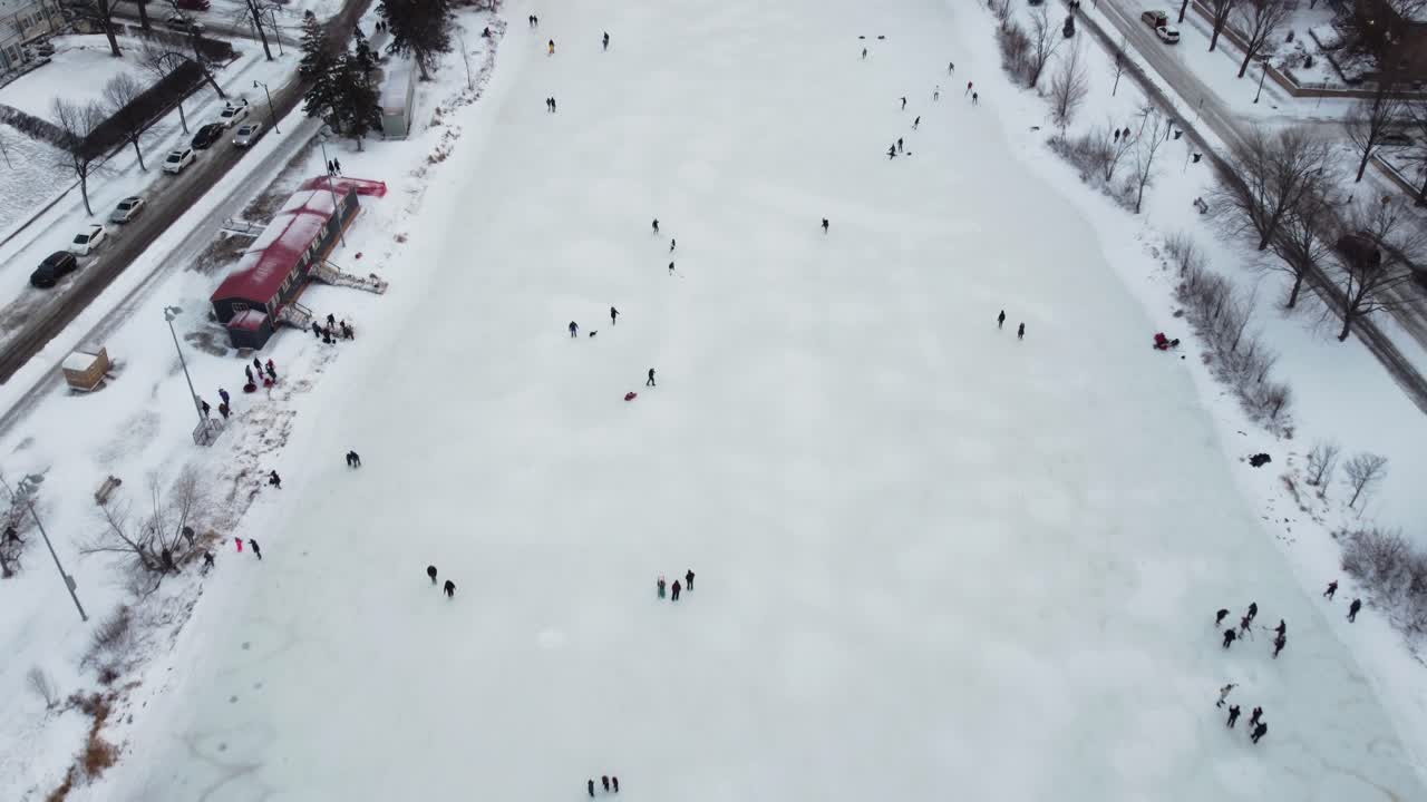 Drone looking down on ice skaters on frozen Lake of the Isles in Minneapolis, MN during winter