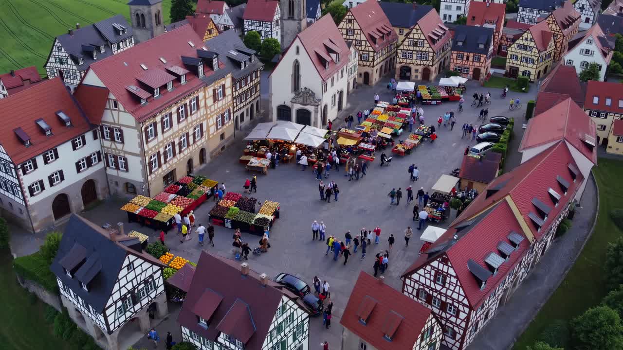 Aerial video captures a quaint village square surrounded by historic buildings and lush fields