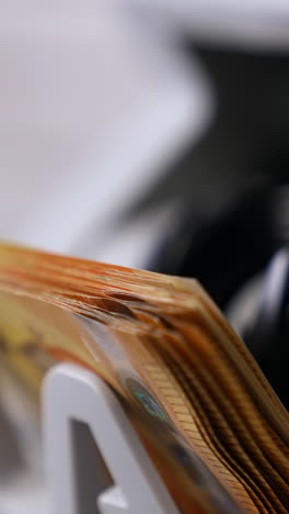 euro currency on counting machine. 50 euro banknotes counting in the machine. counting mechanism is processing euros. female hand taking money. close-up. vertical video