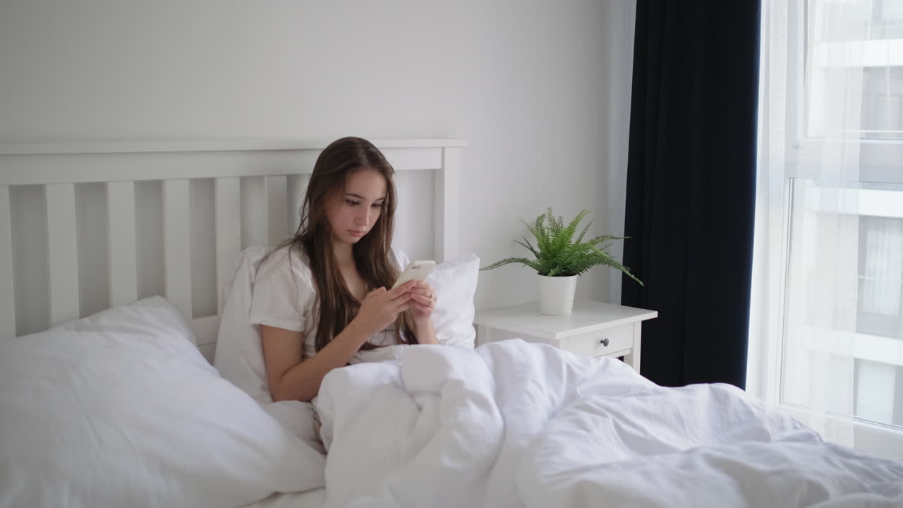 침대에서 전화를 사용하는 여자