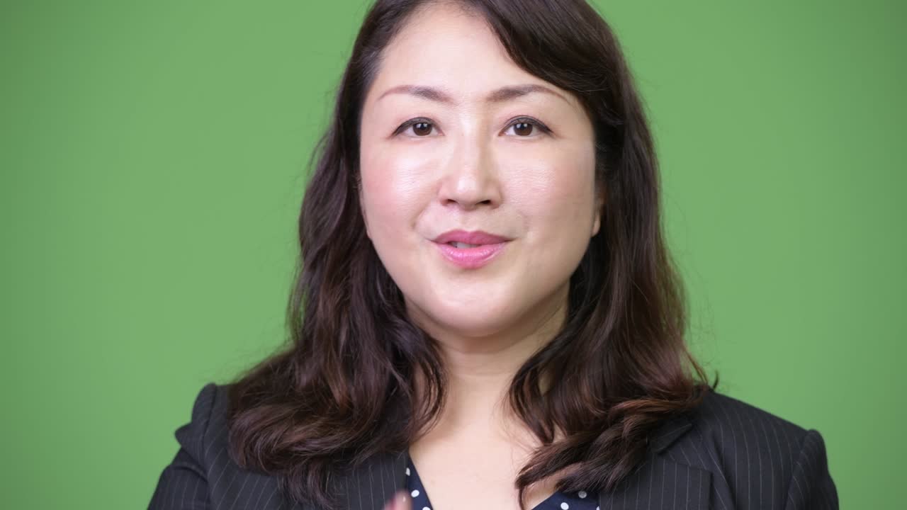 Mature beautiful Asian businesswoman with finger on lips