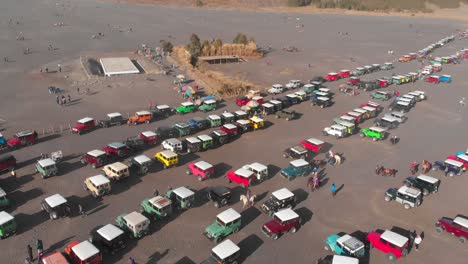 Colorful-jeeps-parked-in-sea-of-sand-in-Tengger-mountains,-tourist-attraction