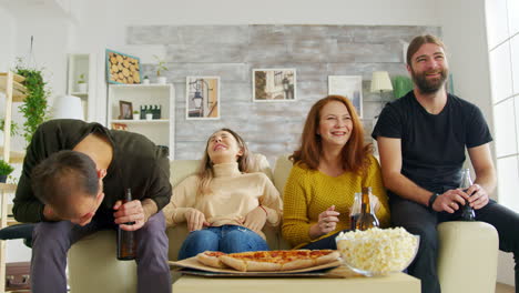 un grupo de amigos riendo mucho mientras una comedia de situación en la televisión