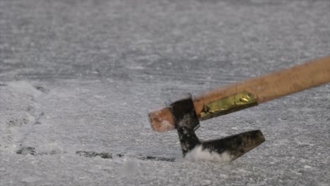 axe breaking ice of a frozen lake close up