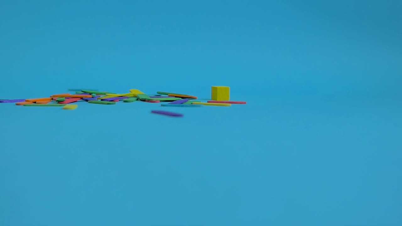 palos de helado de colores cayendo desde arriba sobre un fondo de papel azul