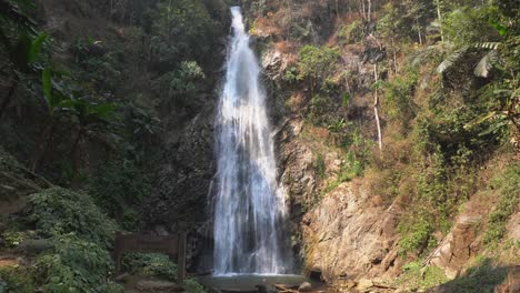 khun korn waterfall splits cliff into sunny and shaded steep jungle