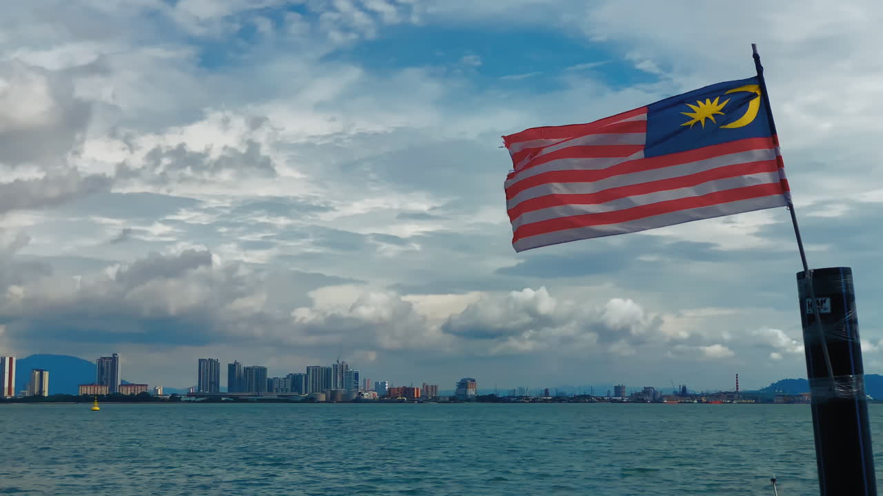 la bandera de malasia ondeando en la brisa, contra el horizonte de butterworth en penang, malasia.