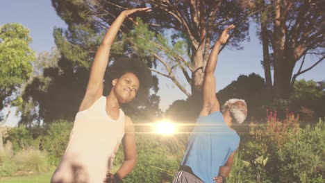 animation of light trails over african american couple doing yoga, stretching, slow motion