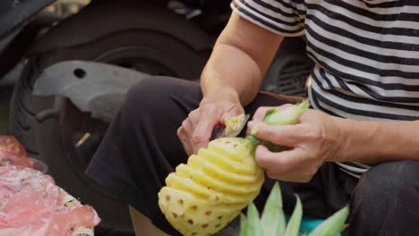 Close-up-footage-of-a-woman-skillfully-cutting-a-pineapple-in-the-streets-of-Hanoi,-Vietnam