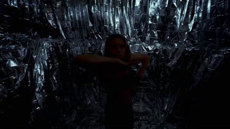 woman expressively dancing contemporary choreography against foil background