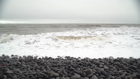 Winter-Tide-splashing-in-towards-camera-over-rocky-beach-at-Dunraven-Bay,-South-Wales