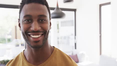portrait of happy african american man smiling in living room at home, in slow motion, copy space