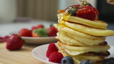 pouring honey on healthy homemade pancakes with fruit in slow motion