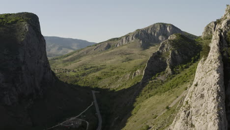 reverse aerial dolly flying through cheile valisoarei recreation area above road, trailhead parking area