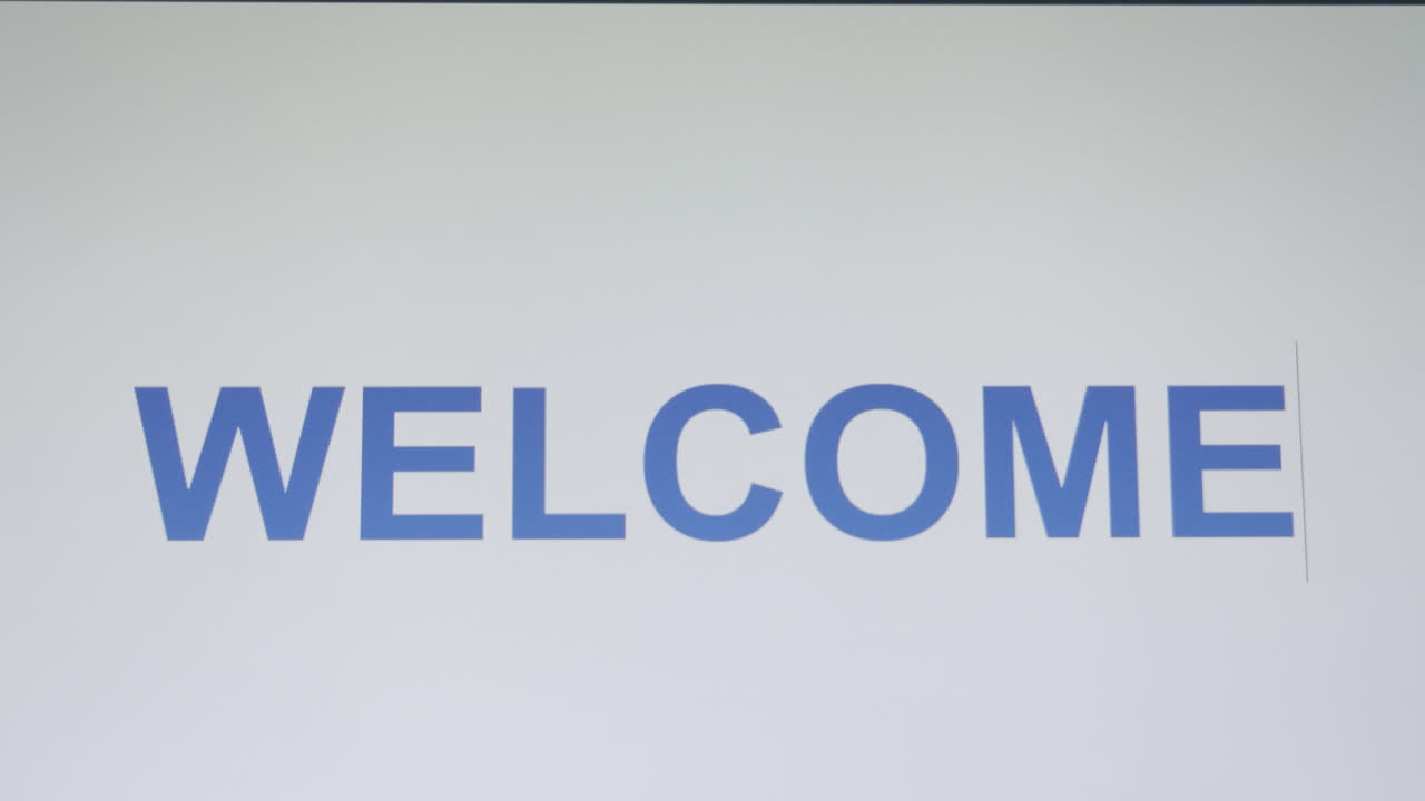 Close-up shot of computer screen showing the word welcome being typed one letter at a time