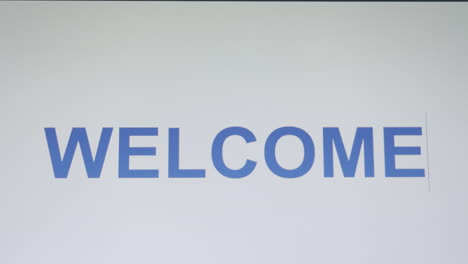 close-up shot of computer screen showing the word welcome being typed one letter at a time