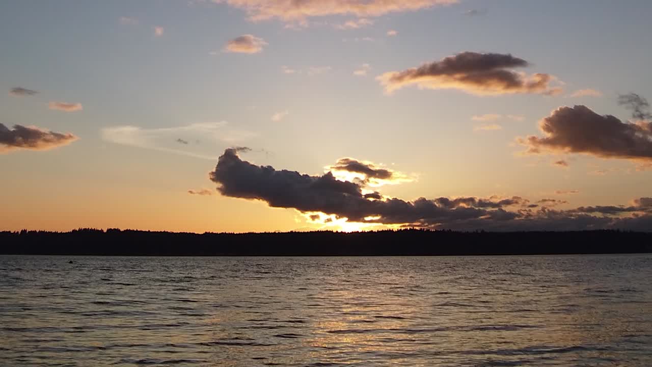 Beautiful hyper time lapse golden hour to blue to black clouds boiling sunset looking out over Puget Sound, pan right zoom in