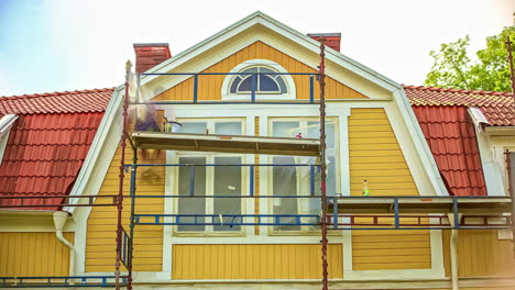 time-lapse of men on scaffolding painting house orange hyper lapse