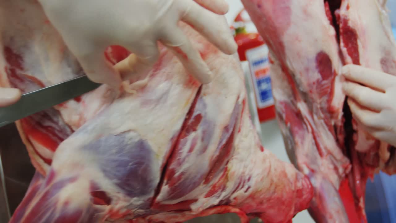 macellaio che taglia la carne in una fabbrica di carne