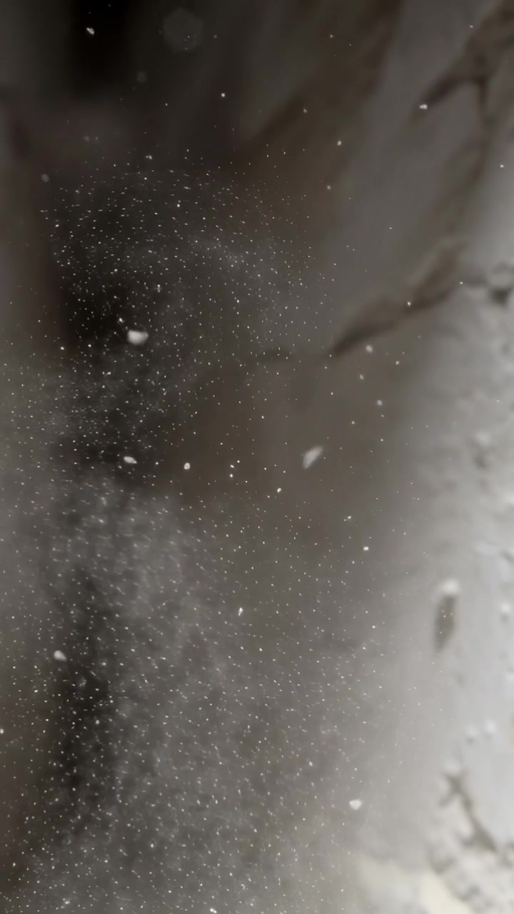 Video verticale: Granelli di polvere e scaglie che si spostano a causa di una corrente d'aria e si depositano nello spazio fino all'intonaco, con bokeh.